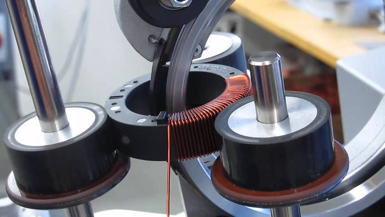 Automated toroidal winding equipment winding copper coil onto an SMC core